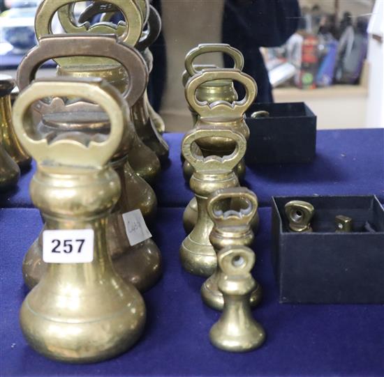 A set of eleven brass bell-shaped weights and another similar large weight